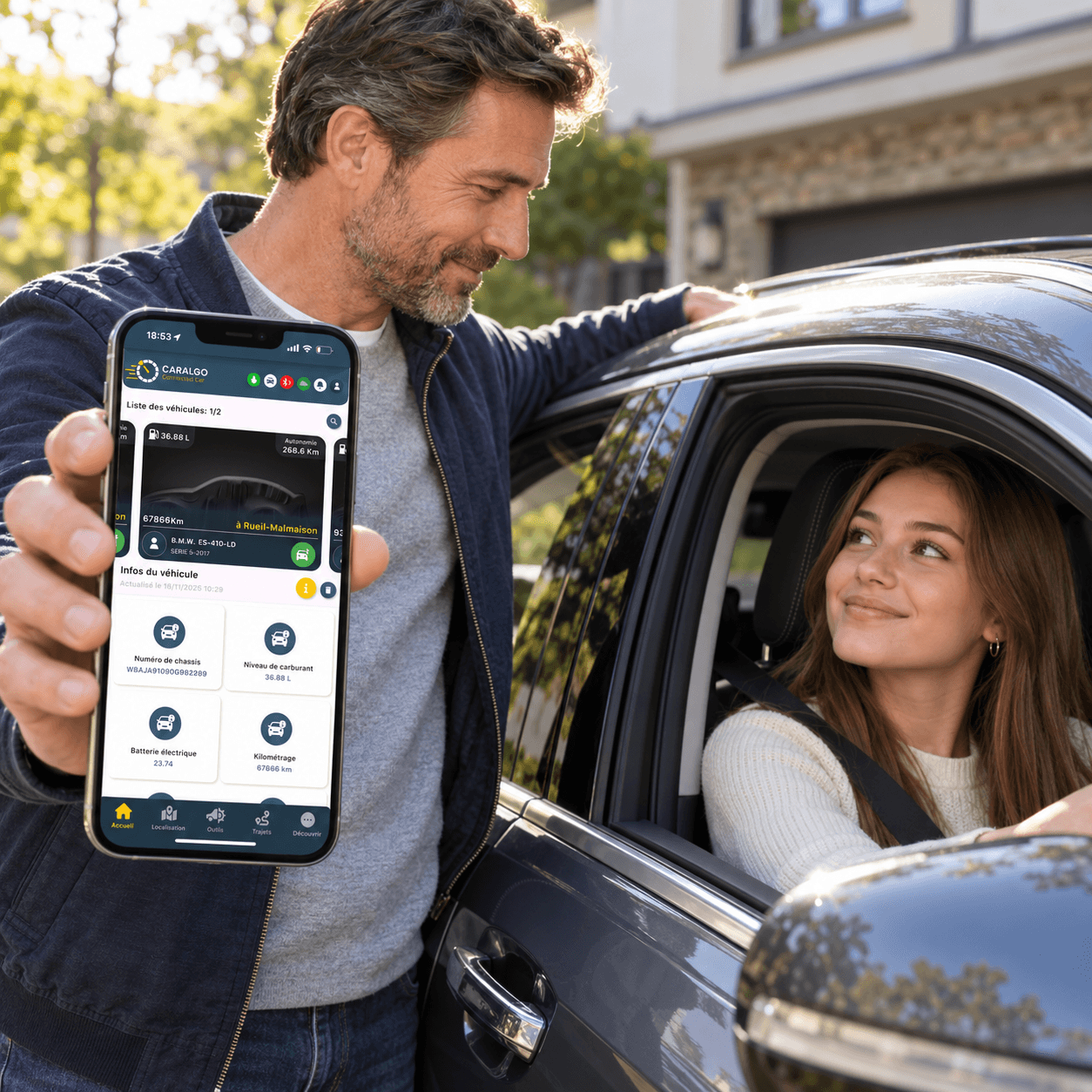 Un père montre l'application CarAlgo sur son smartphone à côté de sa fille, jeune conductrice, au volant